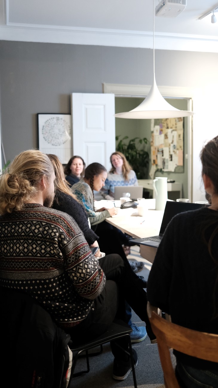 Folk som sitter i et rom rundt et bord