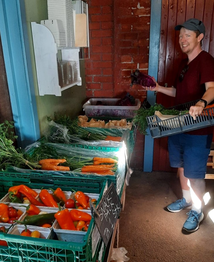 En kunde på Frilund gård plukker opp ferske grønnsaker etter ukens henteliste.