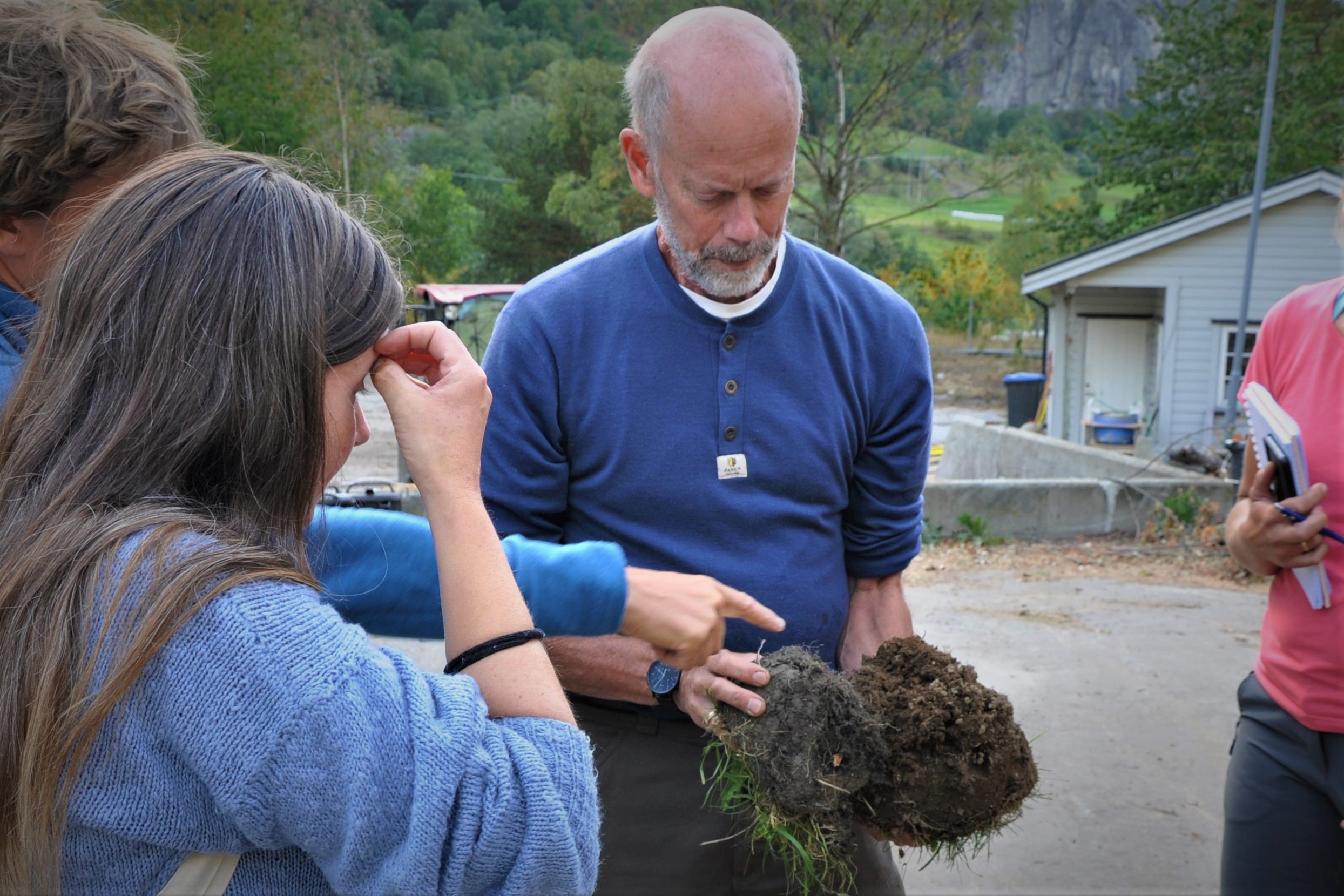 Person i blå genser ser på jordklump med tre andre personer rundt