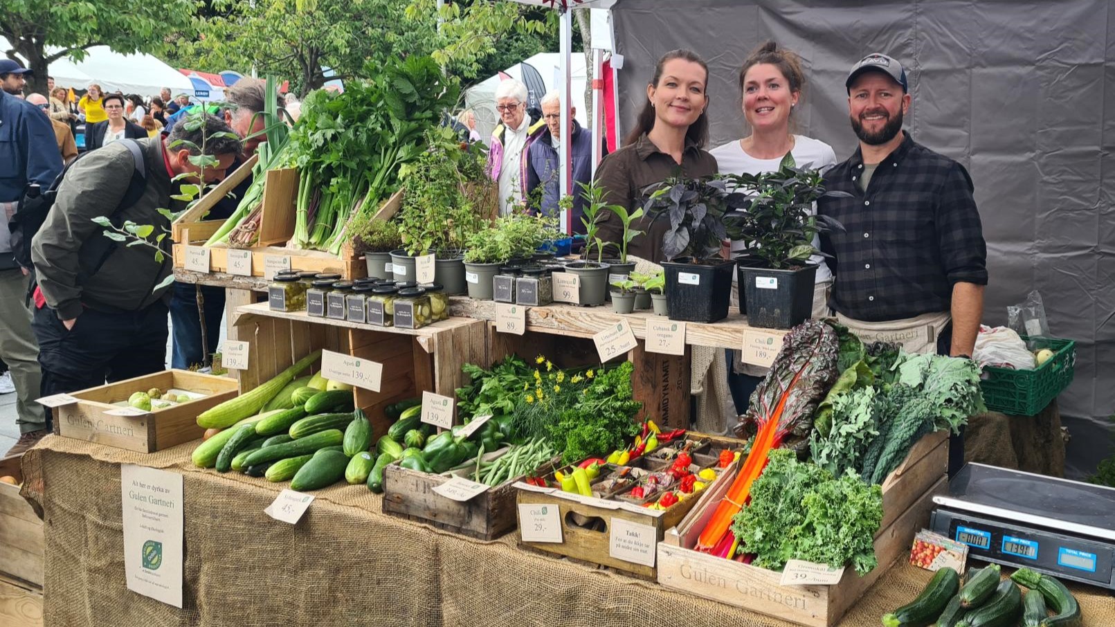 Grønnsaksstand med tre personer i bakgrunnen