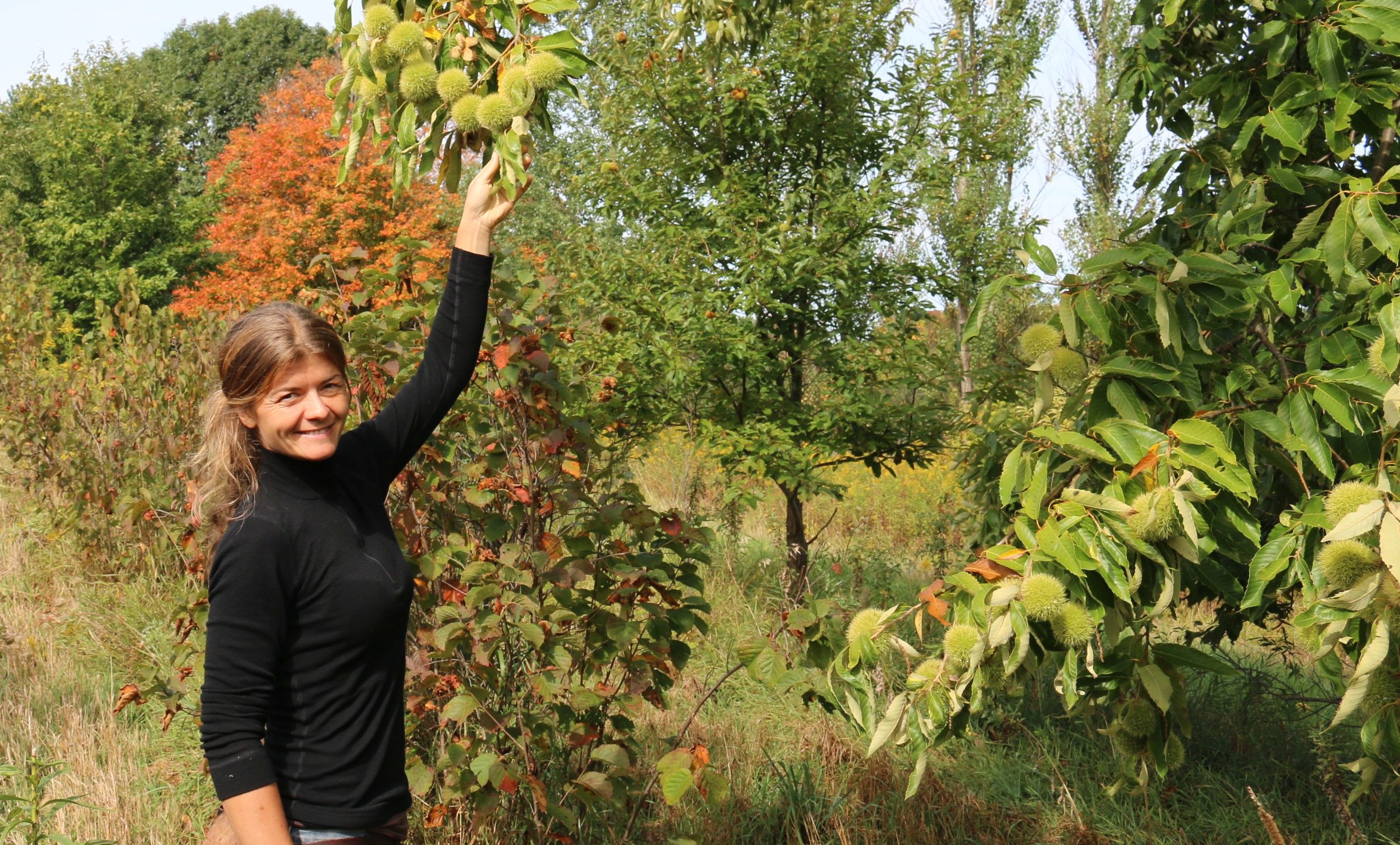 Kvinne viser fram greiner på et frukttre