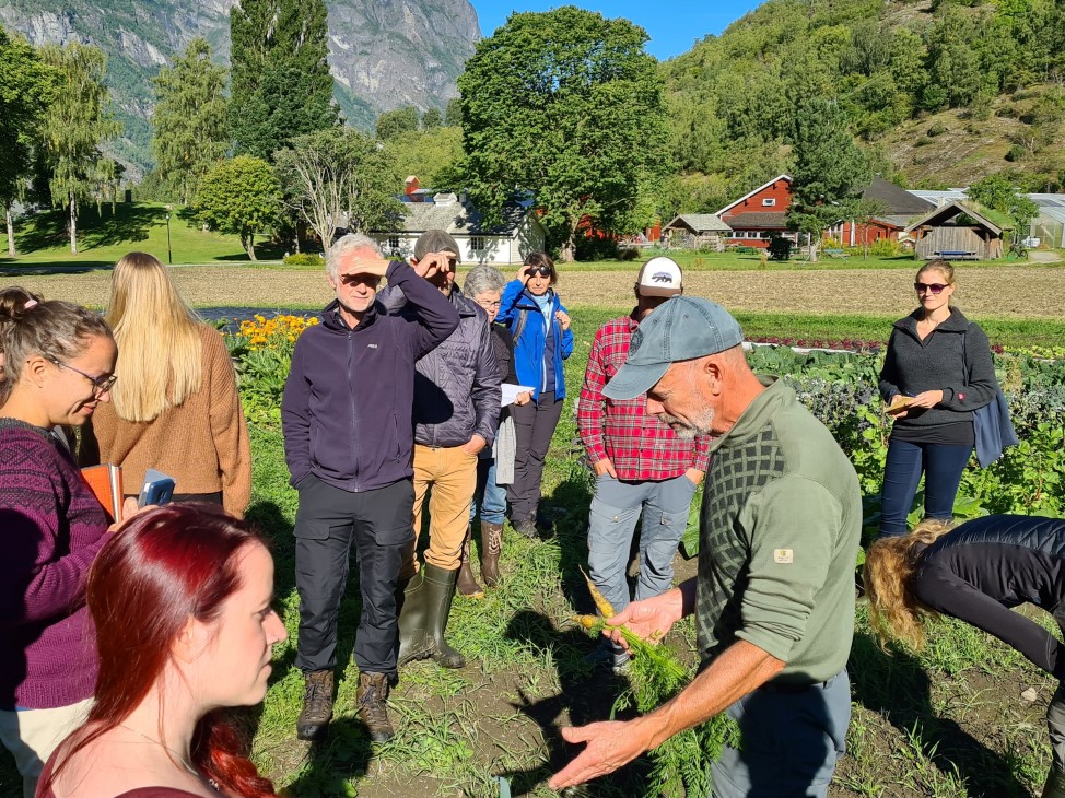 Mange personer ute på åkeren, som diskuterer sammen