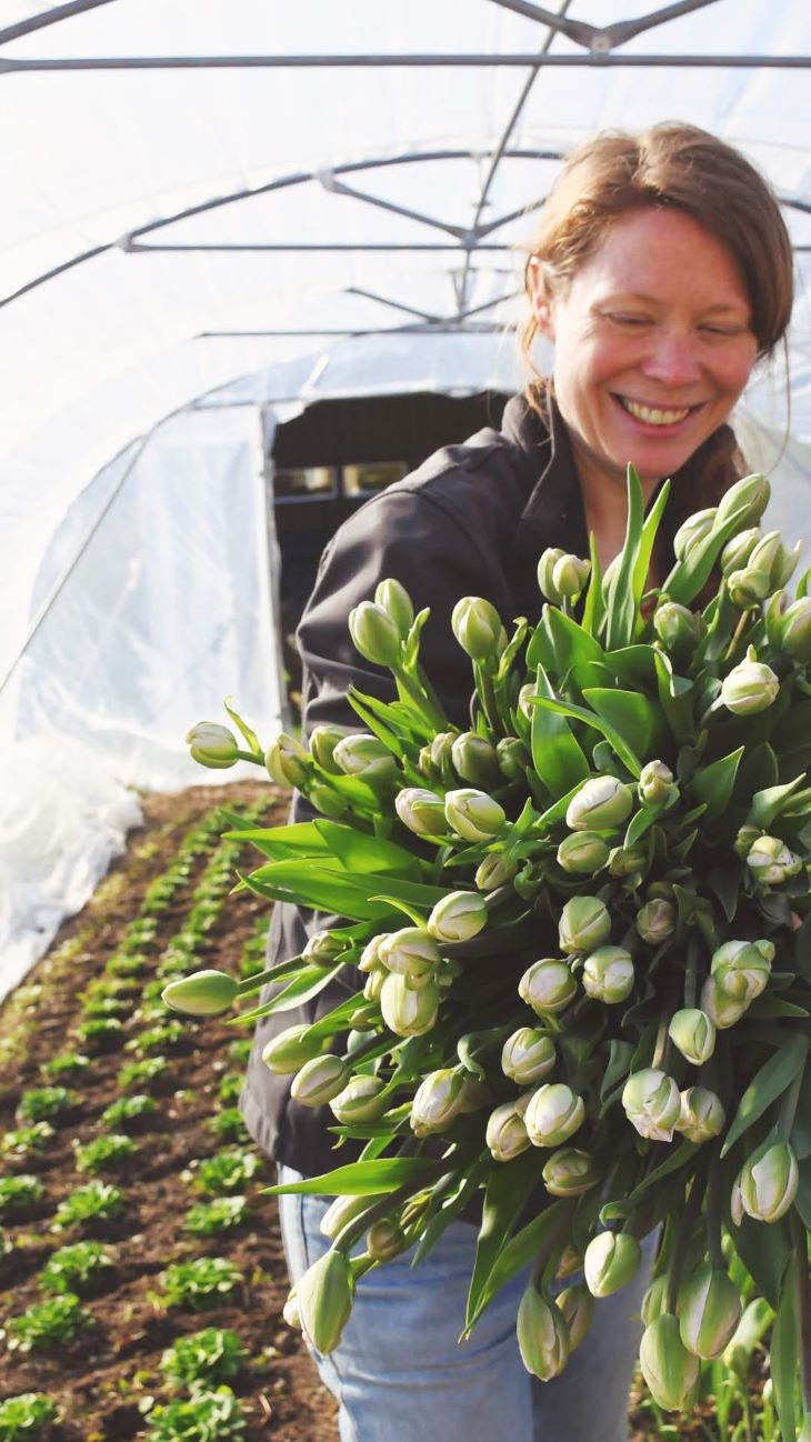 Kvinne med tullipaner i hendene i en plasttunell