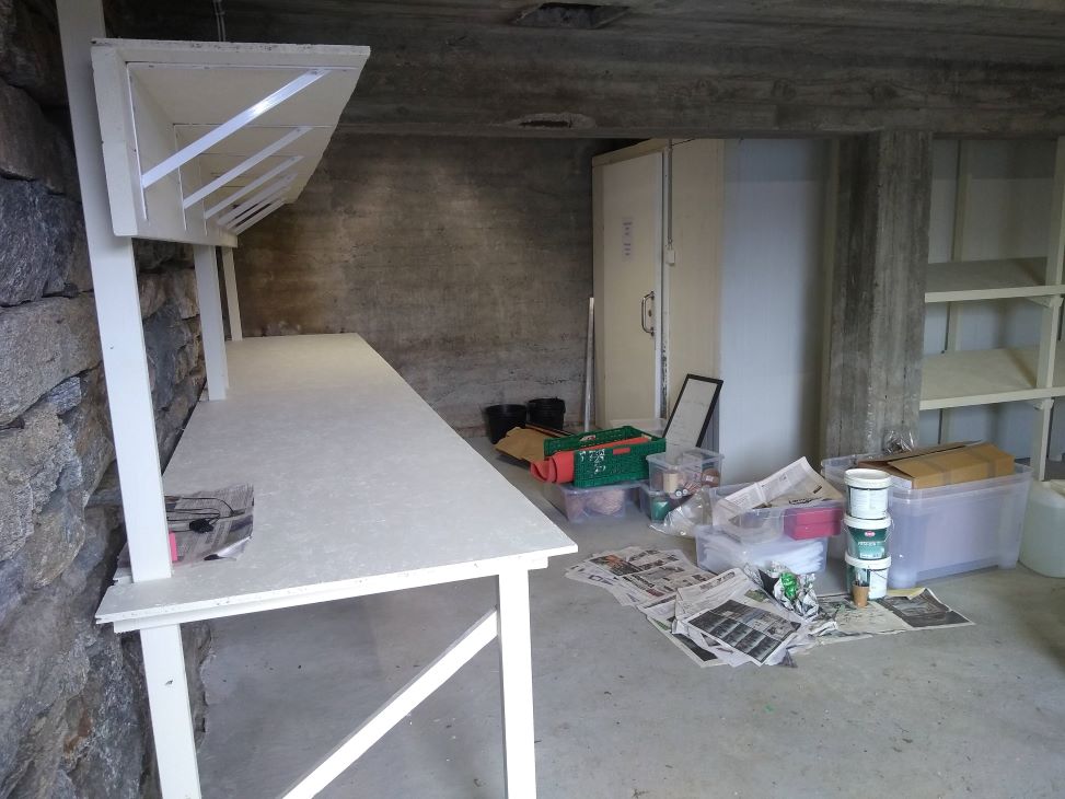 Hvite hyller under bygging i en kjeller