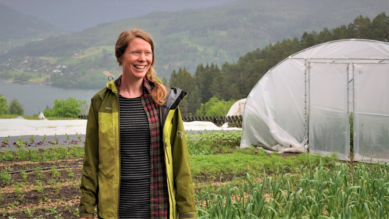 Kvinne som smiler med hvit plasttunnell i bakgrunnen
